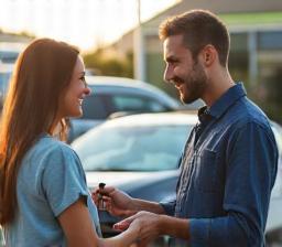 Customer receiving keys, smiling in front of serviced car